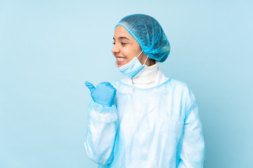 Young surgeon Indian woman in blue uniform pointing to the side to present a product