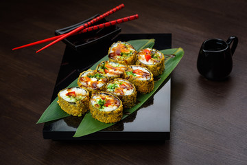 Baked rolls on the board with sauce and red chopsticks