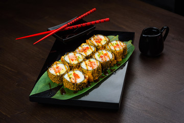 Baked rolls on the board with sauce and red chopsticks
