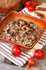Buckwheat porridge with mushrooms in ceramic pot on table
