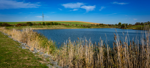 Landscape of Moravian fields with a pond and a beautiful blue sky with white clouds