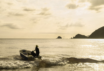 An unidentified man drives boat during sunset in Praia Do Sono, Paraty, Brazil.