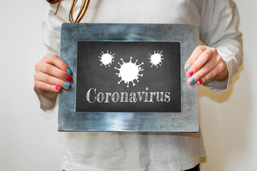 Child holding up a blackboard with the word coronavirus.