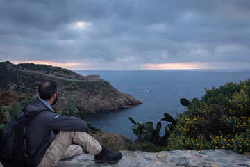 Seated man observing the landscape at sunrise
