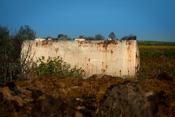 An old, rusted large tanker standing in a field for agriculture