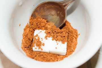 An empty mug filled with cocoa powder and sugar.