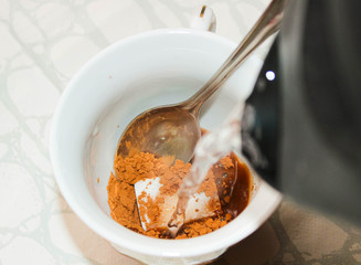 A Cup of cocoa or coffee is filled with boiled water.