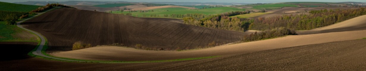 A very large panorama of the beautifully undulating plowed Moravian fields with an asphalt road