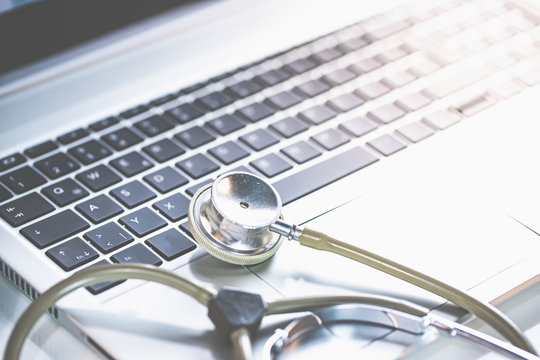 Home Office Medizin - Laptop mit Mundschutz, Stethoskop, Schutz gegen Virus, Infektion, Handy und Sprachassistent. 
