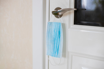concept of protection and safety during the pandemic of the coronavirus covid -19. medical mask hanging on a doorknob