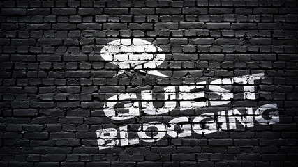 Guest blogging sign, white text on black brick wall