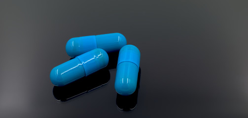 Blue pills closeup on a dark gray and black background