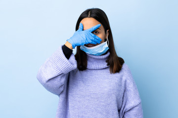 Young brunette mixed race woman protecting from the coronavirus with a mask and gloves over...