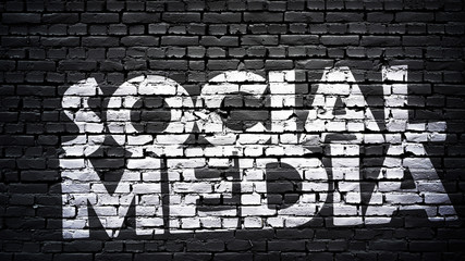 Social media sign, white text on black brick wall