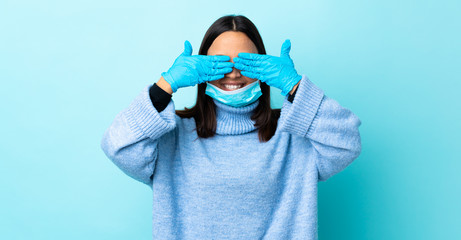 Young brunette mixed race woman protecting from the coronavirus with a mask and gloves over...