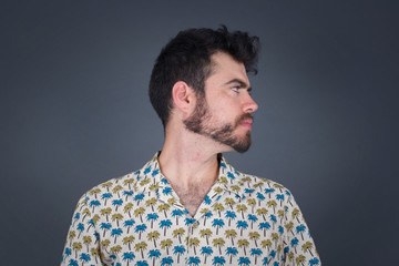 Fototapeta premium Profile of serious man with healthy pure skin has contemplative expression ready to have outdoor walk isolated over grey studio wall with copy space.