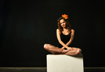 girl in lotus position meditates with lotus flower on a black background