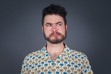Obraz premium Photo of amazed puzzled young Caucasian male with ginger hair knot, curves lips and has worried look, sees something awful in front, isolated on white background, dressed in jean overalls.