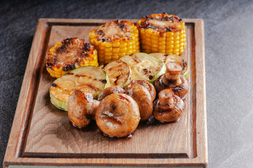 grilled vegetables, mushrooms, corn, zucchini: on a wooden board