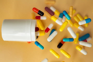 bright colored medical capsules for levitation spilling from a container. Capsules on a yellow background that fall down.