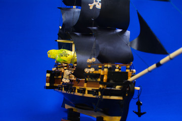 Wooden model of a handmade pirate warship on which a parrot sits.