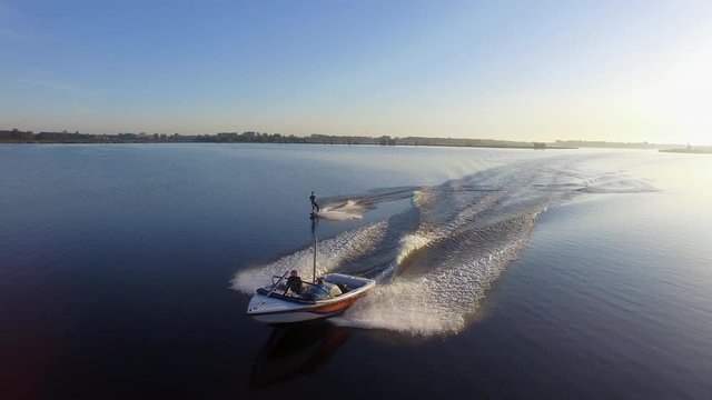 Cinematic aerial shot of a wakeboarder jumping wake to wake behind a speedboat