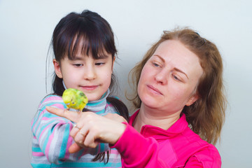 mother and daughter communicate with their tame yellow parrot.