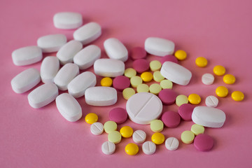 Obraz na płótnie Canvas Assorted pharmaceutical medicine pills. Multi-colored pills of different shapes on a light pink background.