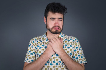 Sad pretty guy feeling upset while spending time at home alone. Handsome young blond male  staring at camera with unhappy or regretful look standing indoors.