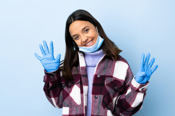 Young brunette mixed race woman protecting from the coronavirus with a mask and gloves over...