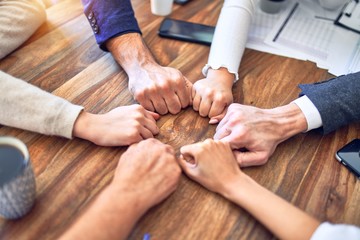 Group of business workers standing bumping fists at the office