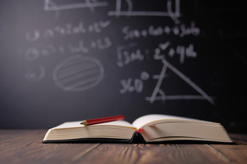 Open books on the table against black board.