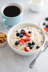 Oatmeal porridge with berries and cup of coffee on table. Healthy breakfast, vegan vegetarian food