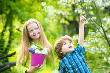 Save world concept. Two little children holding flowers in pot together for prepare plant on ground.