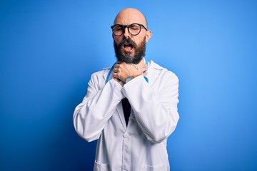 Handsome bald doctor man with beard wearing glasses and stethoscope over blue background shouting suffocate because painful strangle. Health problem. Asphyxiate and suicide concept.