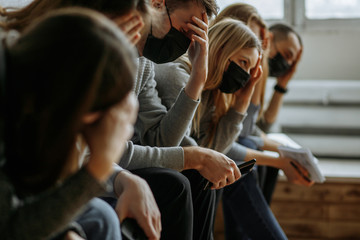 caucasian people have headache and fever heat.they sit in the line, wearing protective medical masks against transmissible infectious diseases and as protection against the influenza in public place