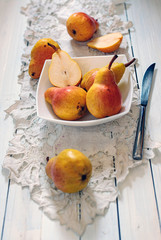front view of juicy pears in whiite bowl and knife aside on white wooden table