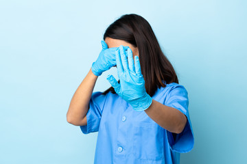 Surgeon woman over isolated blue background making stop gesture and covering face