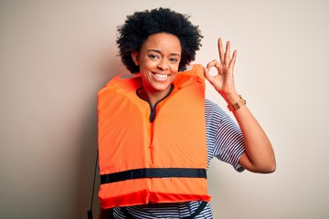 Young African American afro woman with curly hair wearing orange protection lifejacket smiling...