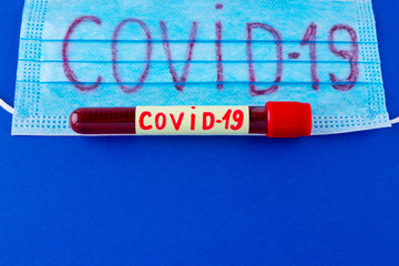 COVID-19. Test tube with blood identified by the COVID-19 coronavirus on classic blue background....