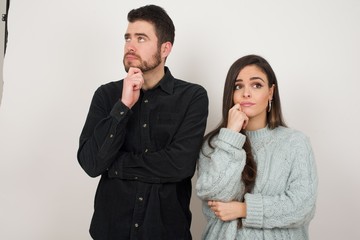 Portrait of thoughtful  woman keeps hand under chin, looks away trying to remember something or listens something with interest, dressed casually, poses indoors. Youth concept.