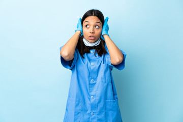 Surgeon woman over isolated blue background frustrated and covering ears