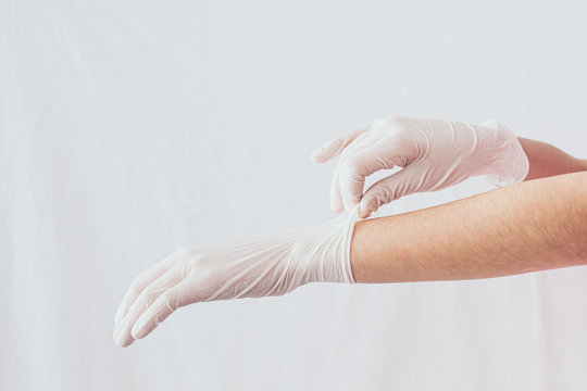 Putting Disposable Sterile White Gloves On White Background