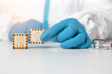 The doctor holds two wooden cubes with the number 21 together, closeup