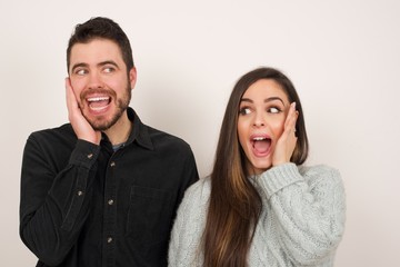 Amazement - woman excited looking to the side hand on face. Surprised happy young woman looking sideways in excitement. Caucasian female model on gray background.