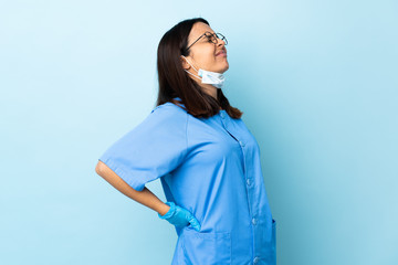 Surgeon woman over isolated blue background suffering from backache for having made an effort