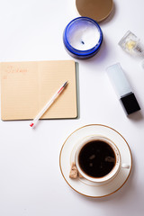 Obraz na płótnie Canvas cup of coffee with diary, and care cosmetics around white background. life style flat lay