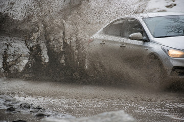 Car motion through big puddle of water splashes from the wheels on the street road. Water splash...