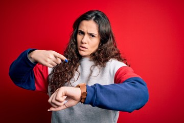 Young beautiful woman with curly hair wearing casual sweatshirt over isolated red background In...