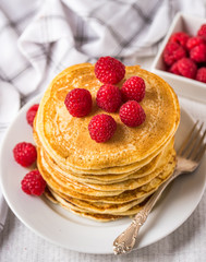 Sweet homemade pancakes with raspberries and on white plate.